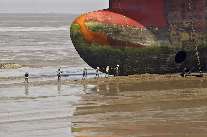 File photo of workers carrying a rope line to fasten a decommissioned ship at the Alang shipyard in Gujarat